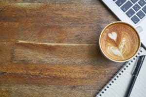 Kaffee neben einem Laptop auf dem Sorglos Büro Schreibtisch